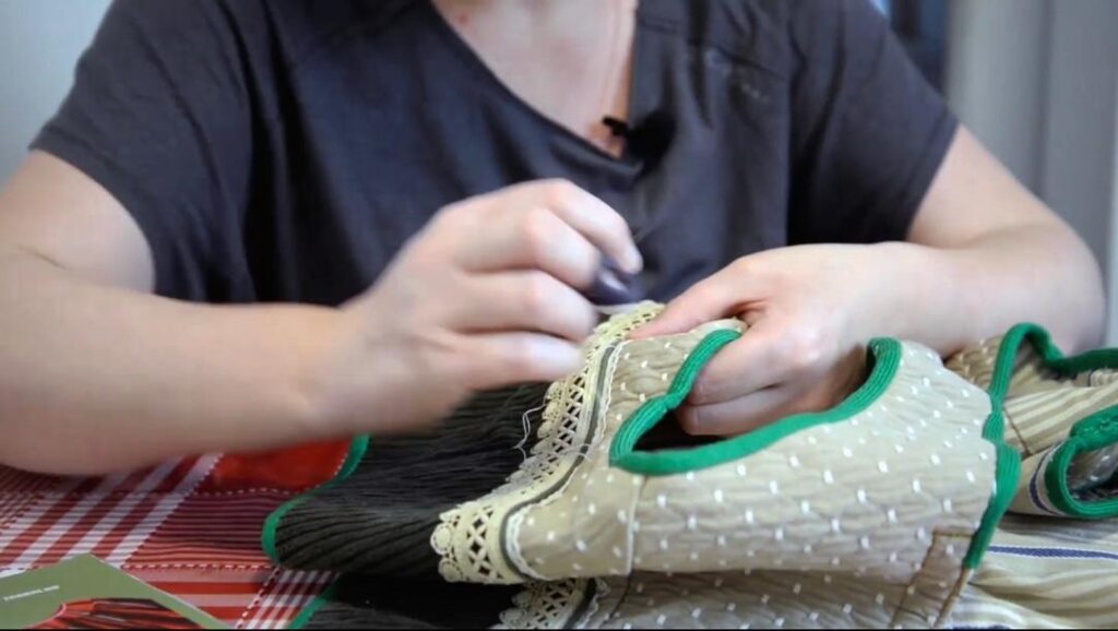 Photogramme extrait de Lá em Baixo : Sofia Costa, couture et manipulation des étoffes.